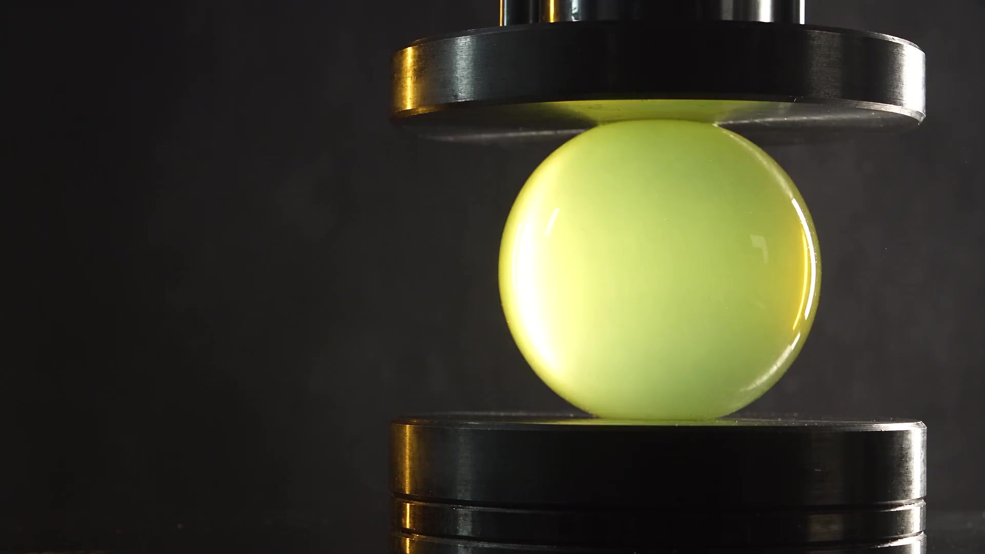 A titanium press squeezing a luminous yellow core